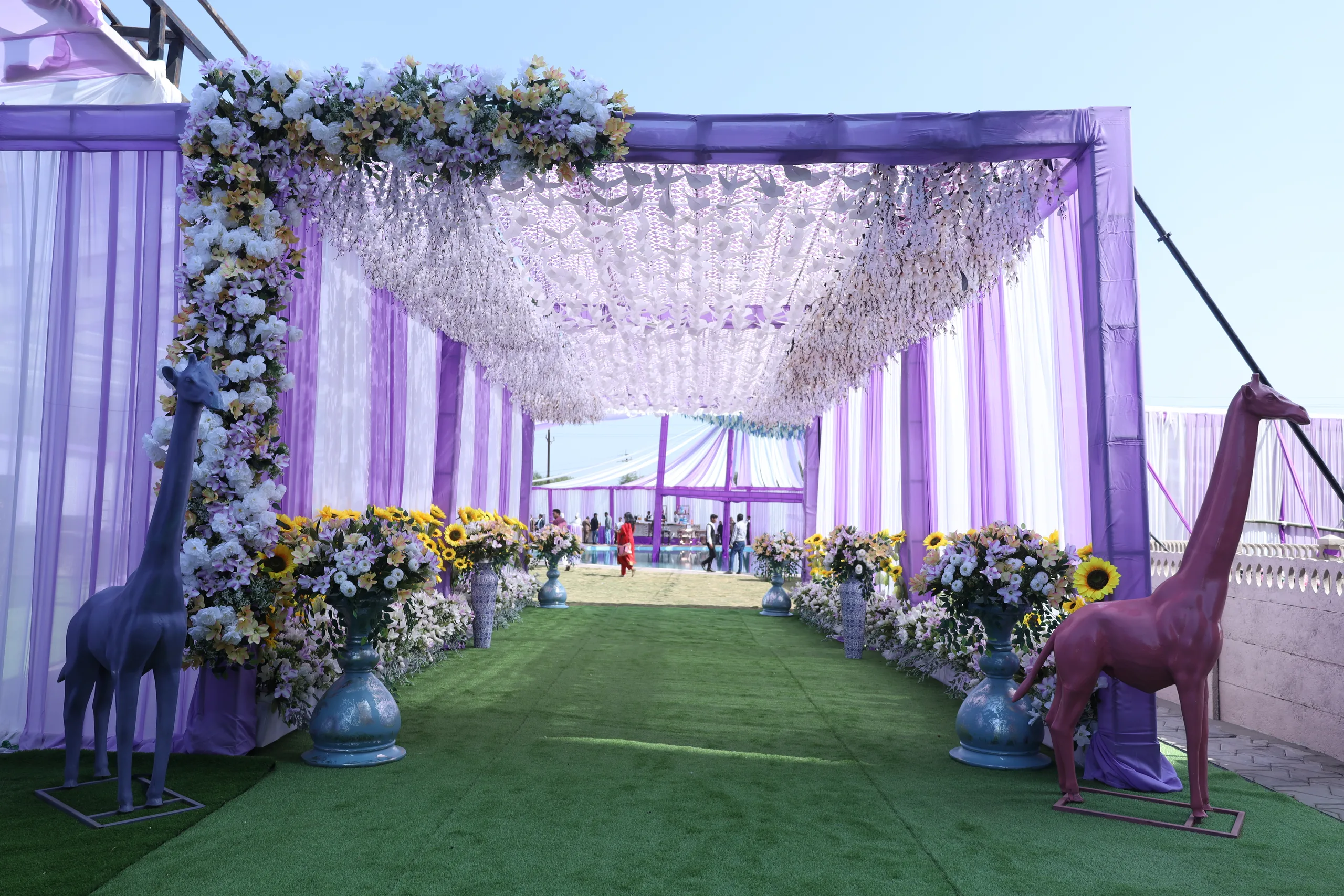 Garlanded ceremony walkway at Vetiver Grand: floral urns and sculpted giraffes lining the aisle to the vows.