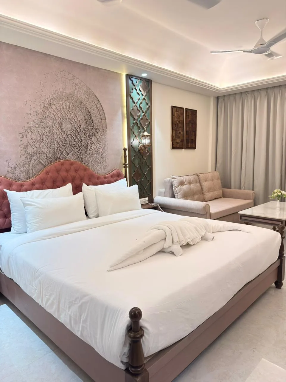 Executive king room: blush tufted headboard against an engraved arch mural, with a sofa sitting area alongside.